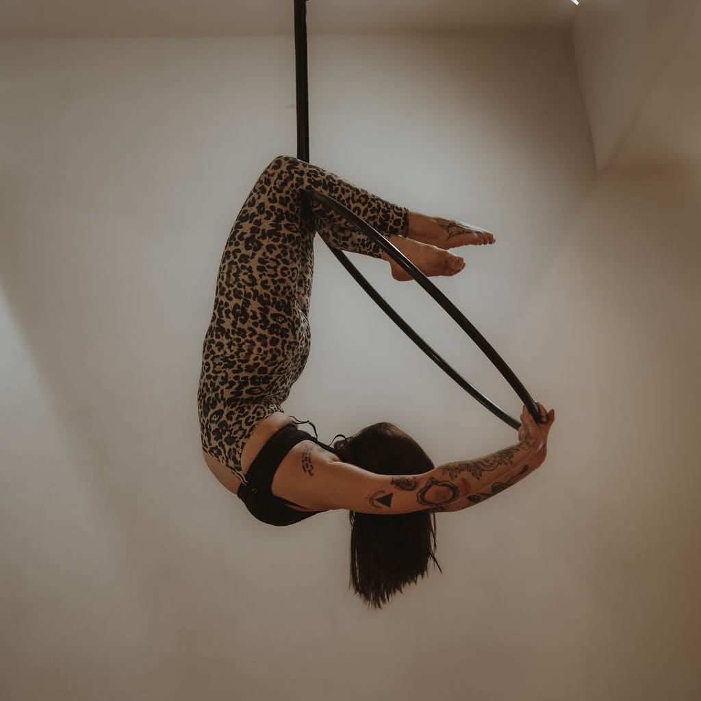 Person in a leopard print outfit hanging upside down on a white wall